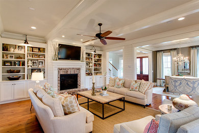 Photo of a large classic open plan living room in Charleston with white walls, medium hardwood flooring, a standard fireplace, a brick fireplace surround and a wall mounted tv.