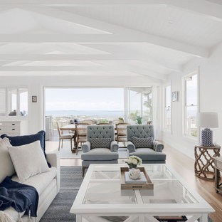 This is an example of a large beach style open concept living room in Brisbane with white walls, a wall-mounted tv and beige floor.