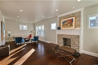 Example of a large transitional enclosed dark wood floor and brown floor living room design in Denver with a standard fireplace, a stone fireplace and white walls
