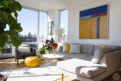 Medium sized modern mezzanine living room in New York with white walls, light hardwood flooring and a freestanding tv.