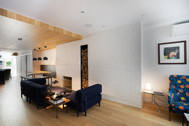 Exemple d'un salon moderne de taille moyenne et ouvert avec une salle de réception, un mur blanc, parquet clair, une cheminée standard, un manteau de cheminée en brique et un sol beige.