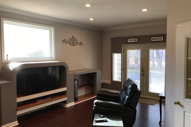 Example of a mid-sized transitional enclosed dark wood floor and brown floor living room design in Other with gray walls, no fireplace and a media wall