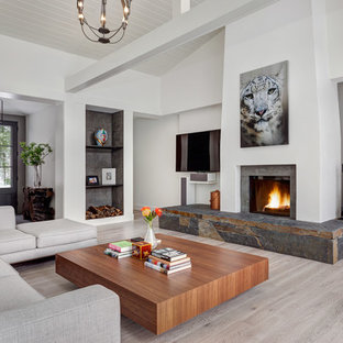 Example of a mid-sized trendy open concept light wood floor and gray floor living room design in Bridgeport with white walls, a standard fireplace, a stone fireplace and a wall-mounted tv