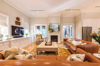 Offenes Klassisches Wohnzimmer mit beiger Wandfarbe, braunem Holzboden, Kamin, TV-Wand und gelbem Boden in Adelaide