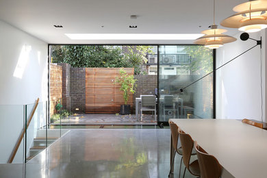 Modern inredning av ett mellanstort allrum med öppen planlösning, med ett finrum, vita väggar, betonggolv och grått golv