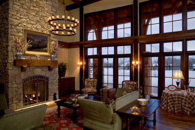 Foto de salón abierto tradicional grande con paredes beige, suelo de madera en tonos medios, todas las chimeneas, marco de chimenea de piedra y televisor retractable