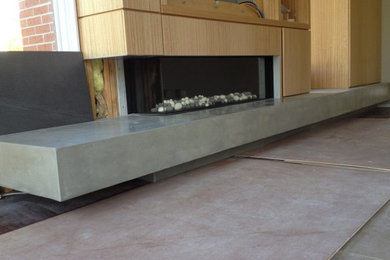 Imagen de salón contemporáneo grande con suelo de cemento, chimenea lineal, marco de chimenea de madera y suelo gris