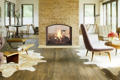 他の地域にある高級な中くらいなコンテンポラリースタイルのおしゃれなリビング (淡色無垢フローリング、石材の暖炉まわり、テレビなし、ベージュの床、ベージュの壁、両方向型暖炉) の写真