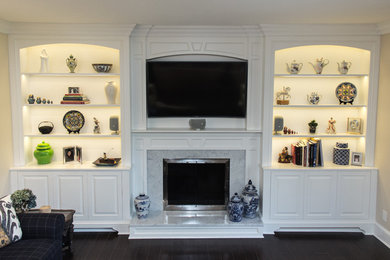 This is an example of a traditional living room in New York with a standard fireplace, a wooden fireplace surround and a built-in media unit.