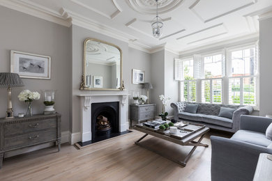 Design ideas for a large classic enclosed living room in London with grey walls, light hardwood flooring, a standard fireplace, a metal fireplace surround, no tv and brown floors.