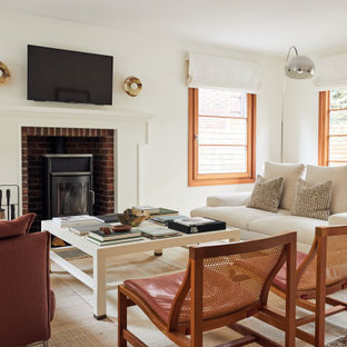 Inspiration for a scandinavian medium tone wood floor and brown floor living room remodel in Minneapolis with white walls, a wood stove and a wall-mounted tv