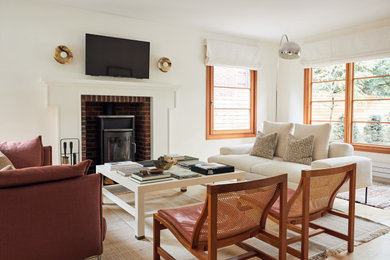 Foto di un soggiorno scandinavo con pareti bianche, pavimento in legno massello medio, stufa a legna, TV a parete e pavimento marrone