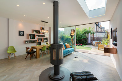 Inspiration for a large contemporary open plan living room in London with a hanging fireplace and grey floors.