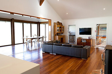 На фото: открытая гостиная комната в стиле модернизм с белыми стенами и телевизором на стене