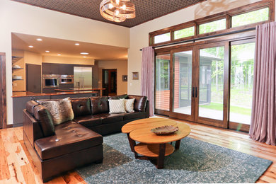 Mittelgroßes, Offenes Modernes Wohnzimmer mit beiger Wandfarbe, braunem Holzboden, Eckkamin und Kaminumrandung aus Stein in Sonstige