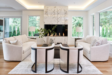 Offenes Modernes Wohnzimmer mit hellem Holzboden, Kamin, Kaminumrandung aus Stein und weißer Wandfarbe in Vancouver