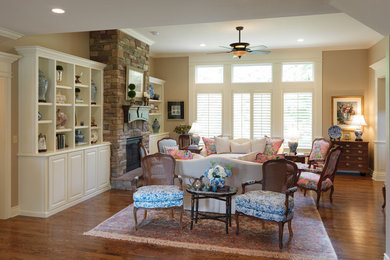Example of a mid-sized classic formal and open concept medium tone wood floor and brown floor living room design in Other with beige walls, a standard fireplace, a stone fireplace and no tv