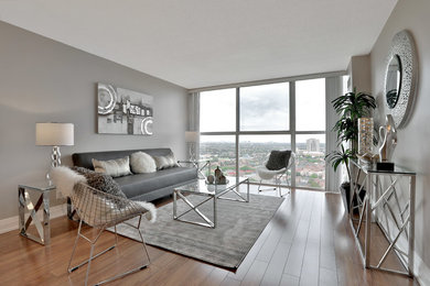 Example of a mid-sized trendy open concept medium tone wood floor and brown floor living room design in Toronto with gray walls and no fireplace