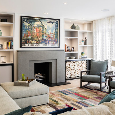 Example of a mid-sized transitional enclosed medium tone wood floor and brown floor living room design in London with beige walls, a standard fireplace, no tv and a stone fireplace