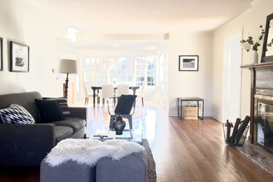 Example of a small transitional formal and open concept medium tone wood floor and brown floor living room design in Chicago with white walls, a standard fireplace, a wood fireplace surround and no tv