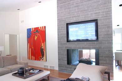 シカゴにあるトランジショナルスタイルのおしゃれなLDK (白い壁、無垢フローリング、両方向型暖炉、タイルの暖炉まわり、壁掛け型テレビ、茶色い床) の写真