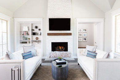オースティンにある高級な広いトランジショナルスタイルのおしゃれなLDK (グレーの壁、濃色無垢フローリング、標準型暖炉、石材の暖炉まわり、壁掛け型テレビ、ベージュの床) の写真