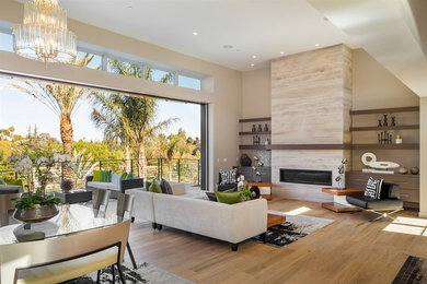 Example of a large trendy open concept medium tone wood floor living room design in San Francisco with beige walls, a ribbon fireplace and a stone fireplace