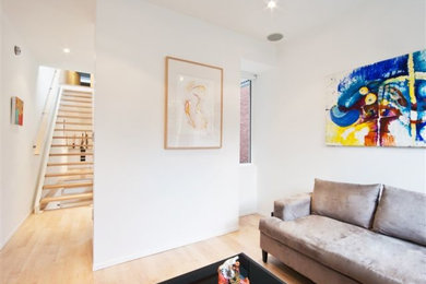 Modelo de salón para visitas abierto minimalista de tamaño medio con paredes blancas, suelo de madera clara y suelo beige