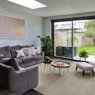 This is an example of a large contemporary open plan living room in London with dark hardwood flooring, no fireplace, a home bar, grey walls and black floors.