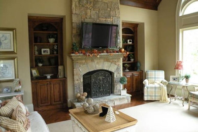 Photo of a medium sized traditional formal open plan living room in Atlanta with beige walls, dark hardwood flooring, a standard fireplace, a stone fireplace surround, a wall mounted tv and brown floors.