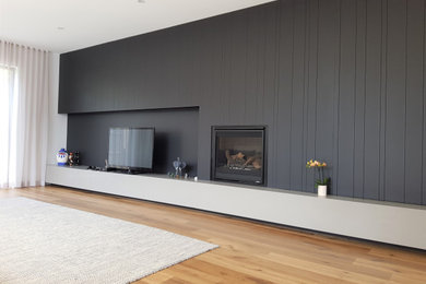 巨大なコンテンポラリースタイルのおしゃれなLDK (白い壁、淡色無垢フローリング、標準型暖炉、金属の暖炉まわり、据え置き型テレビ、茶色い床) の写真