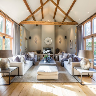 This is an example of a medium sized country formal open plan living room in Gloucestershire with grey walls, light hardwood flooring, a wood burning stove and beige floors.