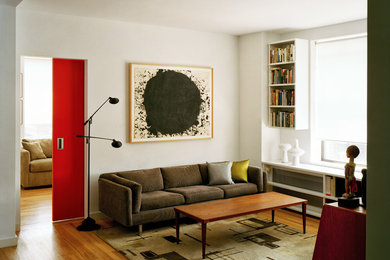 Imagen de biblioteca en casa cerrada contemporánea pequeña sin chimenea con paredes blancas, suelo de madera en tonos medios, televisor colgado en la pared y suelo marrón