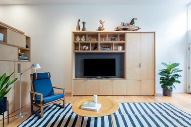 Imagen de salón abierto nórdico de tamaño medio con paredes blancas, suelo de madera clara y pared multimedia