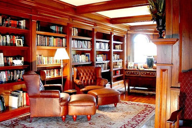 Example of a large classic enclosed medium tone wood floor living room library design in Boston with a standard fireplace and a wood fireplace surround