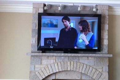 Example of a living room design in Chicago with a standard fireplace, a stone fireplace and a wall-mounted tv