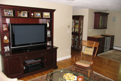 This is an example of a living room in Boston with beige walls, medium hardwood flooring and a built-in media unit.