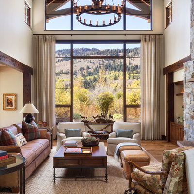 Example of a large mountain style formal and open concept medium tone wood floor and brown floor living room design in Other with beige walls, a standard fireplace and a stone fireplace
