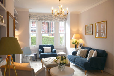 This is an example of a large traditional enclosed living room in London with grey walls, light hardwood flooring, a standard fireplace, a wooden fireplace surround, a wall mounted tv and grey floors.