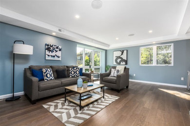 Imagen de salón abierto contemporáneo de tamaño medio con paredes azules, suelo de madera en tonos medios y suelo gris