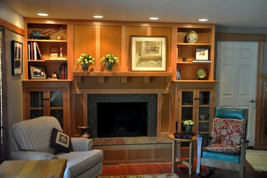 Wohnzimmer mit beiger Wandfarbe, braunem Holzboden, Kamin, gefliester Kaminumrandung und Multimediawand in Boise