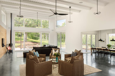 Esempio di un soggiorno moderno aperto con pareti bianche, pavimento in cemento, stufa a legna, TV a parete e pavimento grigio