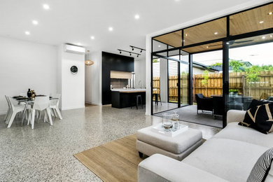 Imagen de salón abierto minimalista con paredes blancas, suelo de cemento y suelo gris