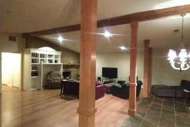 Imagen de salón abierto actual grande sin televisor con suelo de madera clara, chimenea de esquina y marco de chimenea de piedra