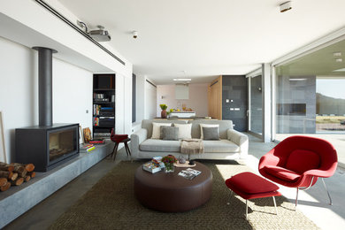 Großes, Offenes Modernes Wohnzimmer mit weißer Wandfarbe, Betonboden, Kamin und Kaminumrandung aus Metall in Barcelona