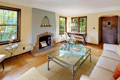 Imagen de salón abierto de estilo americano de tamaño medio con paredes amarillas, suelo de madera clara, todas las chimeneas y marco de chimenea de piedra