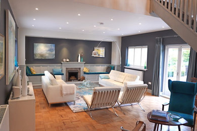 Medium sized contemporary enclosed living room in Surrey with blue walls, light hardwood flooring, a standard fireplace, a brick fireplace surround and orange floors.