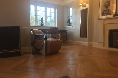 Geräumiges, Abgetrenntes Modernes Wohnzimmer mit grauer Wandfarbe, braunem Holzboden, Kaminofen und Kaminumrandung aus Stein in Sussex