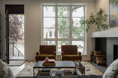 Mittelgroßes, Fernseherloses, Offenes Modernes Wohnzimmer mit weißer Wandfarbe, hellem Holzboden, Kamin, gefliester Kaminumrandung und beigem Boden in Chicago