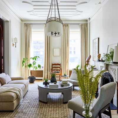 Example of a transitional medium tone wood floor and brown floor living room design in New York with white walls